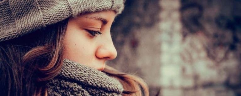 ¿Buscas Psicólogo en Murcia? ¡Conócenos! 7 Chica de perfil con gorro y bufanda de lana, mirada baja y gesto apagado