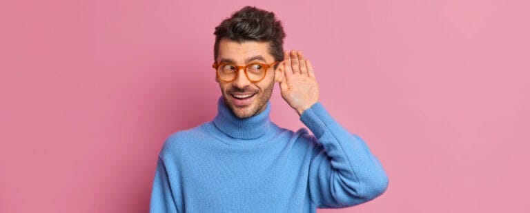 10 Trucos para que todos quieran volver a hablar contigo 7 Hombre con jersey azul se lleva la mano ahuecada a la oreja para escuchar con atención