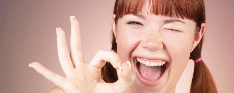 Fibromialgia: ¿Qué es eso? 3 Mujer pelirroja guiña un ojo y hace el gesto de OK, todo aparentemente bien