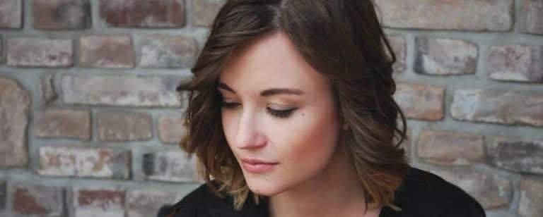 ¿Para qué sirve ir al Psicólogo? 6 Mujer joven con la mirada baja ante una pared de ladrillo, absorta en sus pensamientos