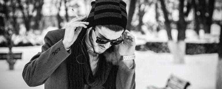 10 motivos por los que deberías ir al psicólogo 4 Hombre con gorro y gafas de sol fumando en un parque nevado, en blanco y negro