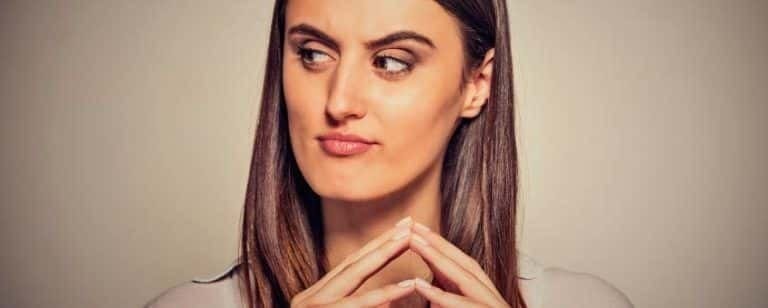 Mujer joven mira de reojo con las yemas de los dedos juntas, en actitud de recelo