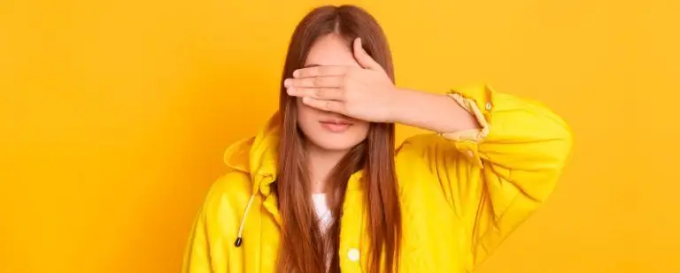 La "ley del hielo": cuando el silencio habla. 3 Joven con chubasquero amarillo se tapa los ojos con la mano, en un gesto de evitación
