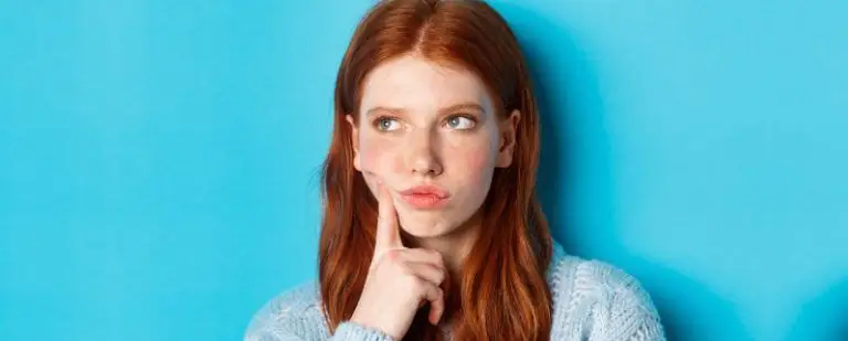 ¿Es normal llorar a menudo? 3 Chica pelirroja con el dedo en la mejilla mira hacia arriba, absorta en una duda