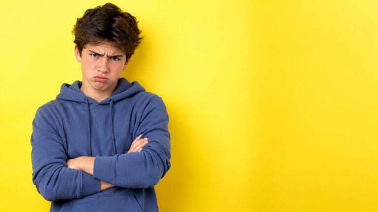 Mi hijo adolescente siempre está enfadado: qué hay debajo de la ira 1 adolescente con una sudadera azul enfadado sobre un fondo de color amarillo